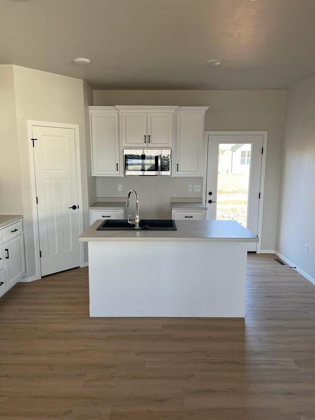 kitchen with stainless steel microwave, white cabinetry, dark wood-type flooring, and a sink