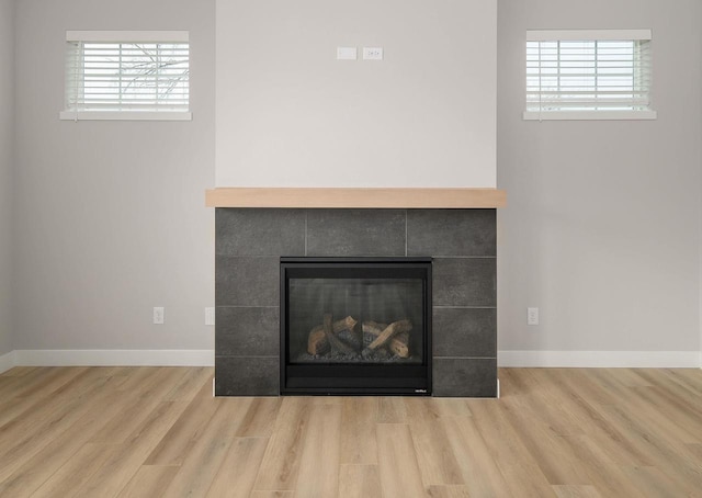 details with a tile fireplace and wood-type flooring