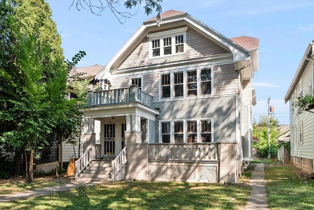 rear view of property featuring a lawn and a balcony