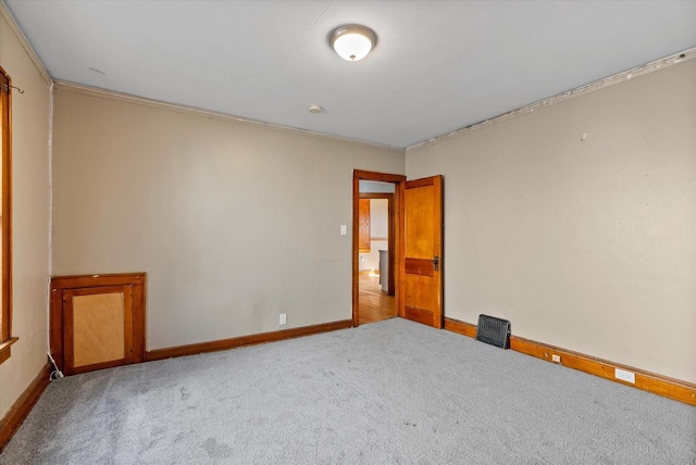 spare room featuring crown molding, carpet flooring, and baseboards