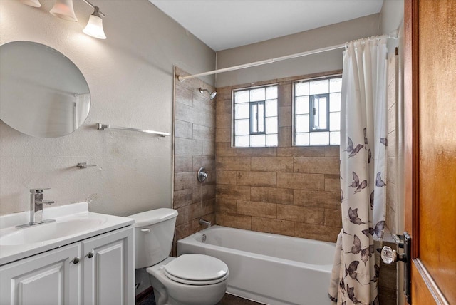 bathroom featuring a textured wall, shower / tub combo with curtain, vanity, and toilet