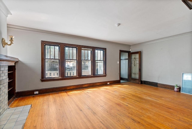 unfurnished living room featuring crown molding, a brick fireplace, light wood-style floors, and a wealth of natural light