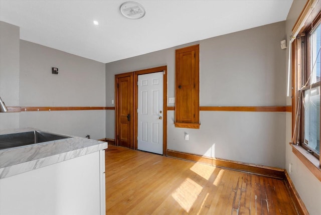 kitchen with baseboards, light wood-style flooring, a sink, light countertops, and brown cabinets