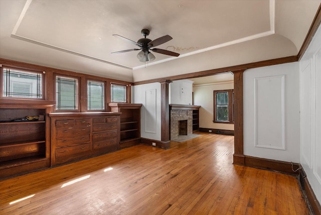 unfurnished bedroom with a raised ceiling, light wood-style flooring, and a fireplace with flush hearth