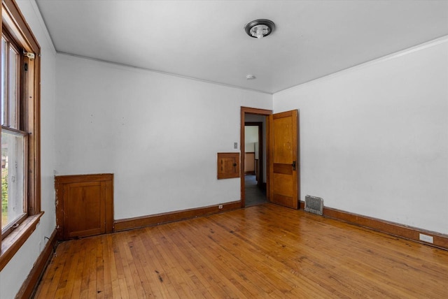 spare room featuring visible vents, baseboards, hardwood / wood-style floors, and ornamental molding