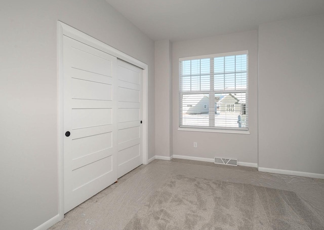 unfurnished bedroom with light colored carpet and a closet