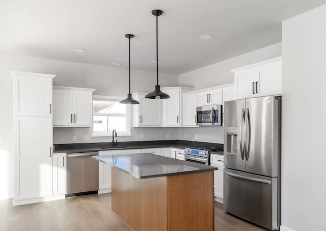 kitchen with appliances with stainless steel finishes, a kitchen island, hanging light fixtures, and sink