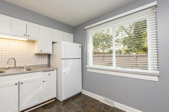 kitchen featuring white cabinets, white fridge, and plenty of natural light