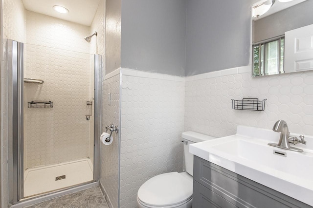 bathroom with tiled shower, vanity, toilet, and tile walls