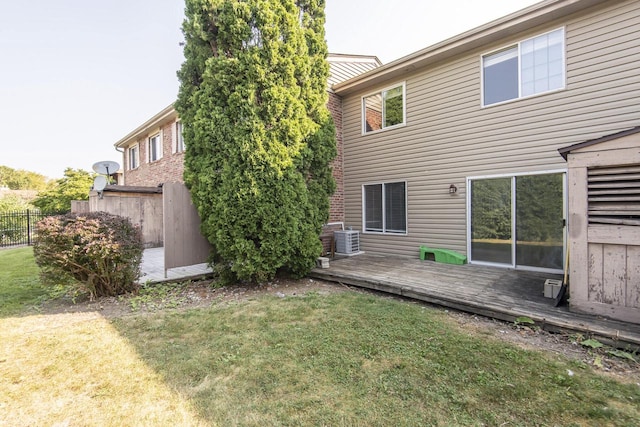 rear view of property with a lawn, a deck, and central AC