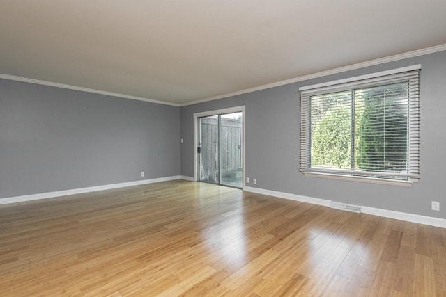 empty room featuring light wood-type flooring and ornamental molding