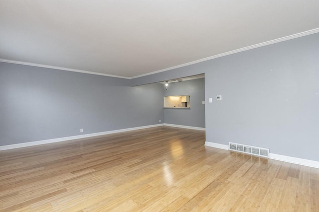 empty room with crown molding and light hardwood / wood-style floors