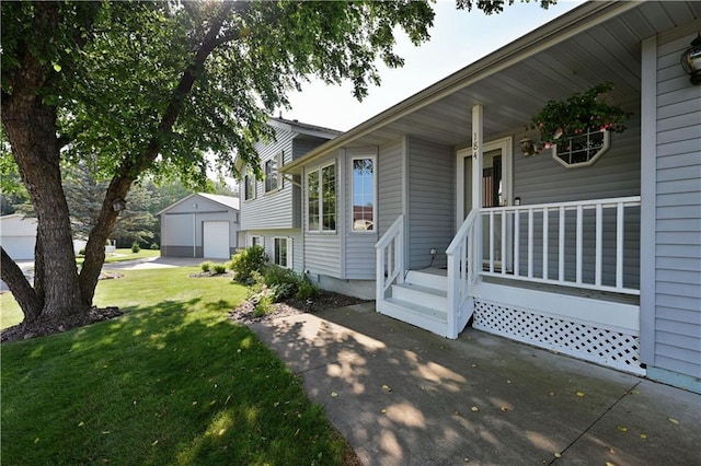 entrance to property featuring a detached garage, a lawn, a porch, and driveway