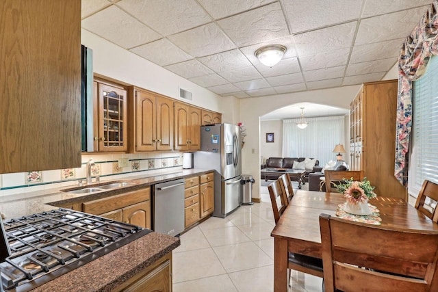 kitchen with light tile patterned floors, stainless steel appliances, a drop ceiling, and sink