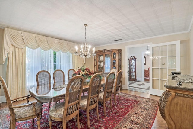 dining space featuring hardwood / wood-style flooring, a notable chandelier, and ornamental molding