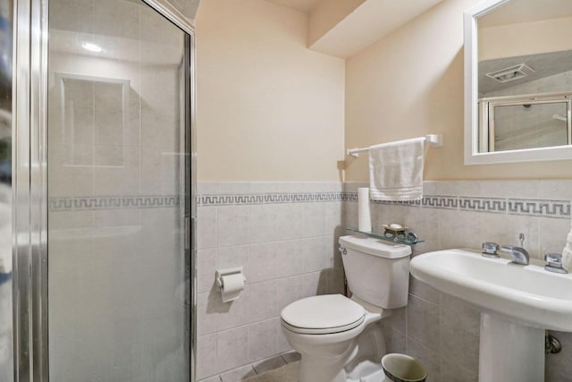 bathroom with tile walls, toilet, a shower with shower door, and decorative backsplash