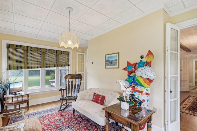 sitting room featuring hardwood / wood-style floors, a paneled ceiling, an inviting chandelier, and ornamental molding