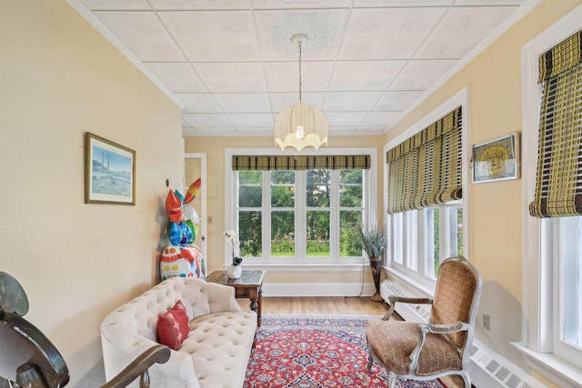 living area featuring ornamental molding, hardwood / wood-style floors, and an inviting chandelier