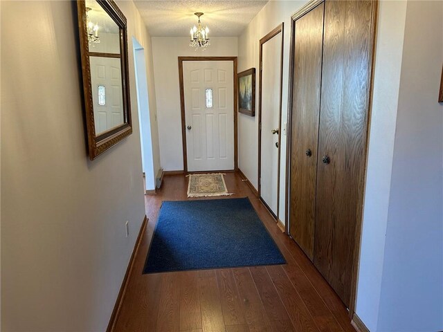 entryway featuring an inviting chandelier, dark hardwood / wood-style flooring, and a textured ceiling