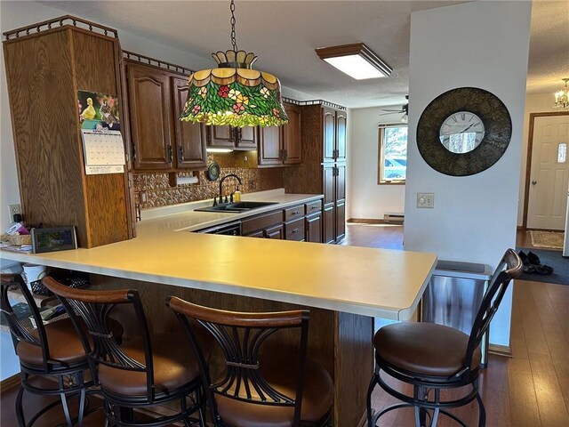 kitchen featuring kitchen peninsula, a kitchen breakfast bar, sink, and dark hardwood / wood-style flooring