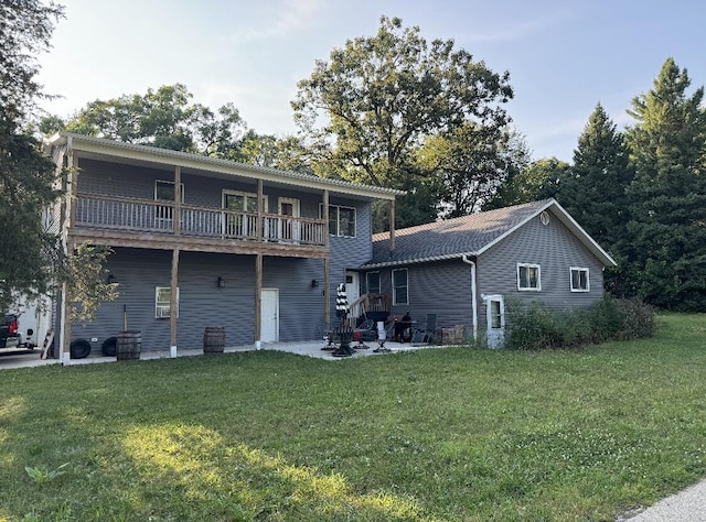 back of property featuring a balcony, a yard, and a patio area