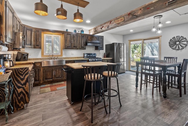 kitchen featuring gas stove, stainless steel fridge, a center island, and a healthy amount of sunlight