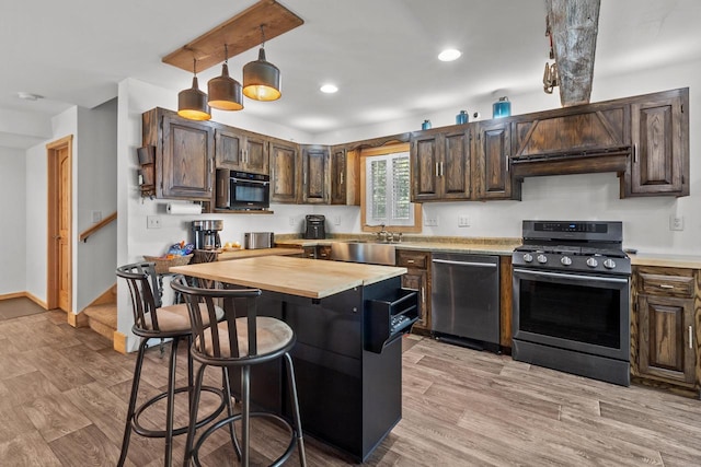 kitchen featuring stainless steel appliances, butcher block counters, dark brown cabinetry, and decorative light fixtures