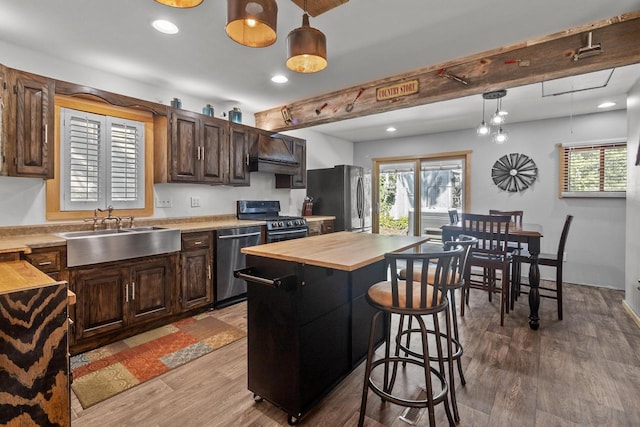 kitchen with a kitchen island, stainless steel appliances, light hardwood / wood-style flooring, decorative light fixtures, and sink