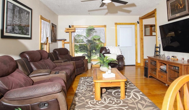 living room with a textured ceiling, wood-type flooring, and ceiling fan