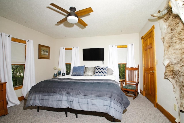 bedroom featuring ceiling fan, a textured ceiling, carpet floors, and multiple windows