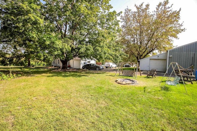 view of yard featuring a garage, an outdoor fire pit, and an outbuilding