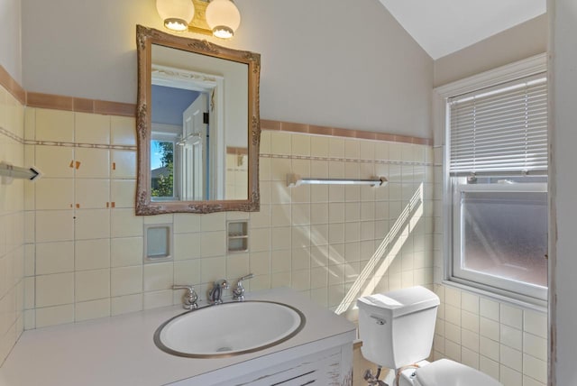 bathroom with tile walls, lofted ceiling, vanity, and toilet