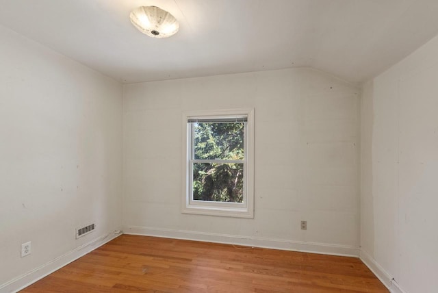 unfurnished room with light wood-type flooring and lofted ceiling