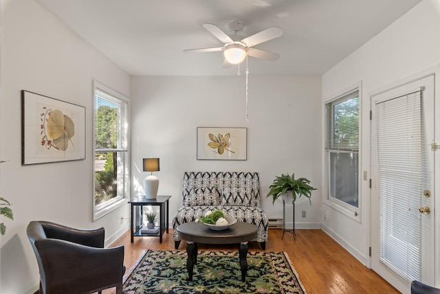 living area featuring ceiling fan, light hardwood / wood-style flooring, and a healthy amount of sunlight