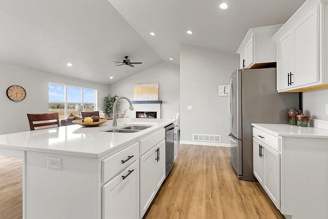 kitchen featuring an island with sink, sink, lofted ceiling, ceiling fan, and light wood-type flooring