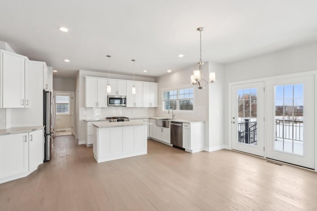 521 N Stone Ridge Dr, Lake Geneva, WI 53147 - kitchen with stainless steel appliances, a kitchen island, light wood-style floors, light countertops, and a chandelier