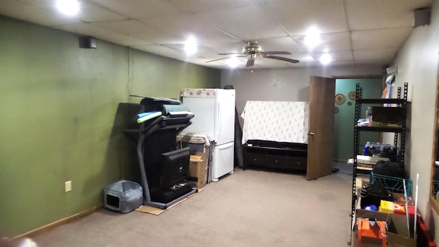 interior space featuring carpet, ceiling fan, white refrigerator, and a drop ceiling