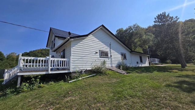 view of side of home with a wooden deck and a yard