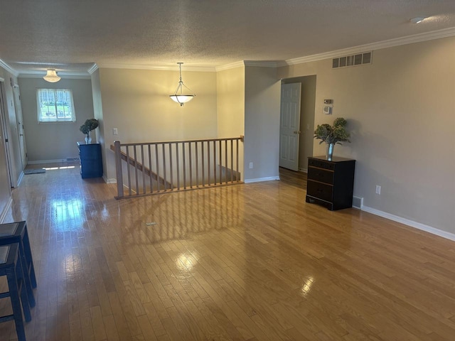 empty room featuring crown molding, hardwood / wood-style floors, and a textured ceiling