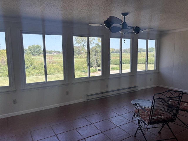 unfurnished sunroom featuring ceiling fan, a wealth of natural light, and baseboard heating