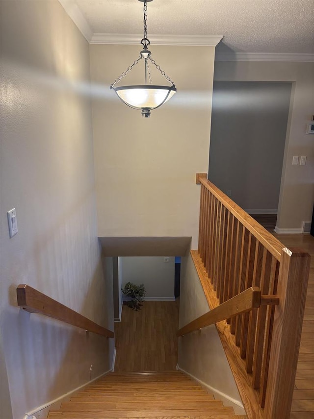 staircase featuring hardwood / wood-style floors, crown molding, and a textured ceiling