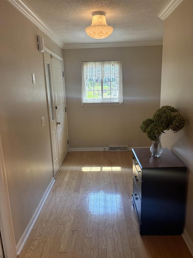 hall with ornamental molding, a textured ceiling, and light hardwood / wood-style floors