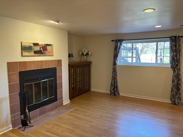 unfurnished living room featuring a tile fireplace and light wood-type flooring