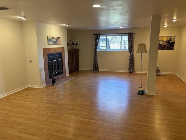 unfurnished living room featuring hardwood / wood-style flooring and a tile fireplace