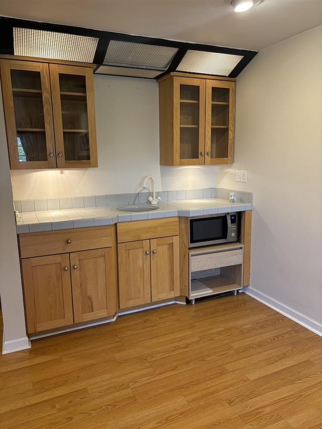 kitchen with sink, tile countertops, and light wood-type flooring