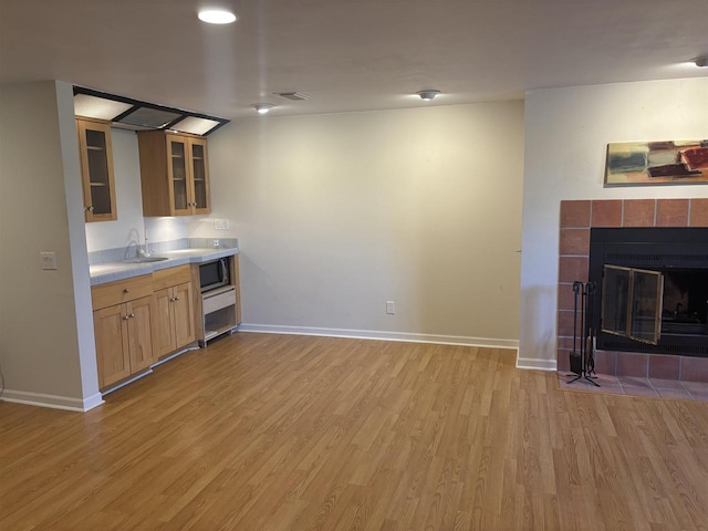 kitchen with sink, light hardwood / wood-style floors, and a tile fireplace