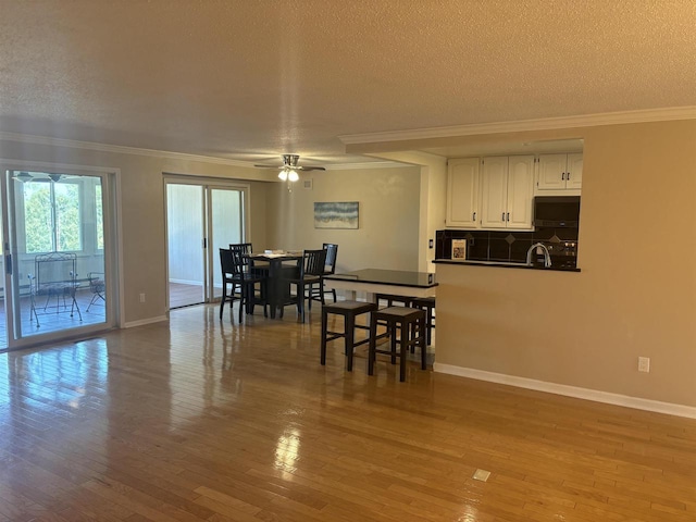 dining space featuring crown molding, sink, a textured ceiling, and light wood-type flooring