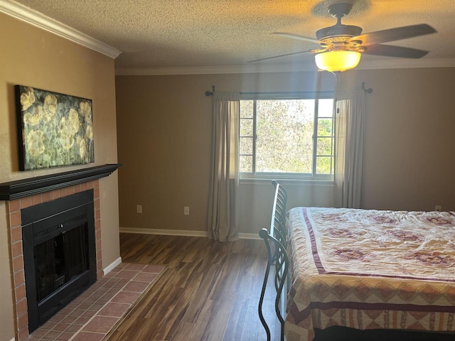 bedroom featuring dark hardwood / wood-style floors, a tiled fireplace, ceiling fan, crown molding, and a textured ceiling