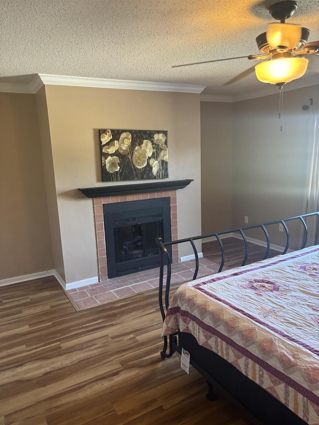 bedroom with hardwood / wood-style flooring, a brick fireplace, a textured ceiling, and ceiling fan