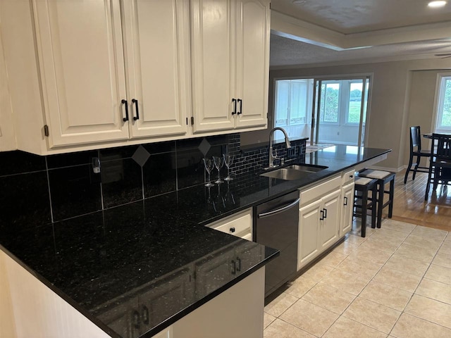 kitchen featuring sink, light tile patterned floors, dishwasher, white cabinets, and dark stone counters